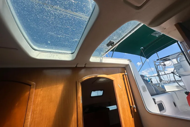 Slide: The Image of Interior view of 2003 Beneteau Oceanis Clipper 331 sailboat with skylight and wooden cabin door. - 59