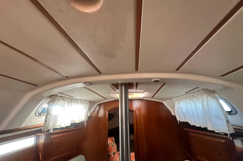 Slide: The Image of Interior of 2003 Beneteau Oceanis Clipper 331 sailboat, featuring wood paneling and curtained windows. - 64