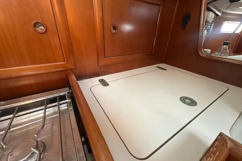 Slide: The Image of Interior of 2003 Beneteau Oceanis Clipper 331 yacht, featuring wooden cabinetry and compact kitchen area. - 67