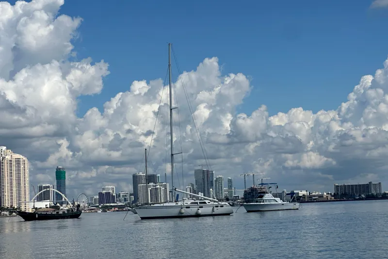 Slide: The Image of Sailboats on calm water with city skyline and clouds in the background. - 72