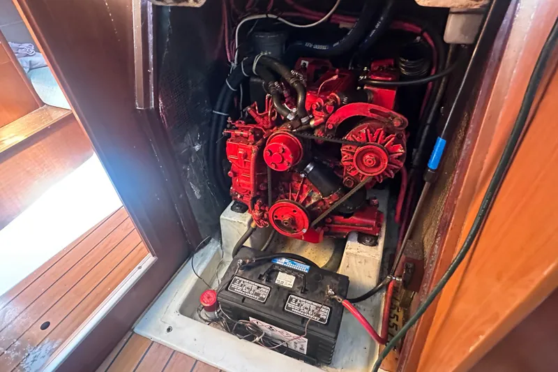 Slide: The Image of Engine compartment of a 2003 Beneteau Oceanis Clipper 331 sailboat, featuring a red engine and battery. - 74