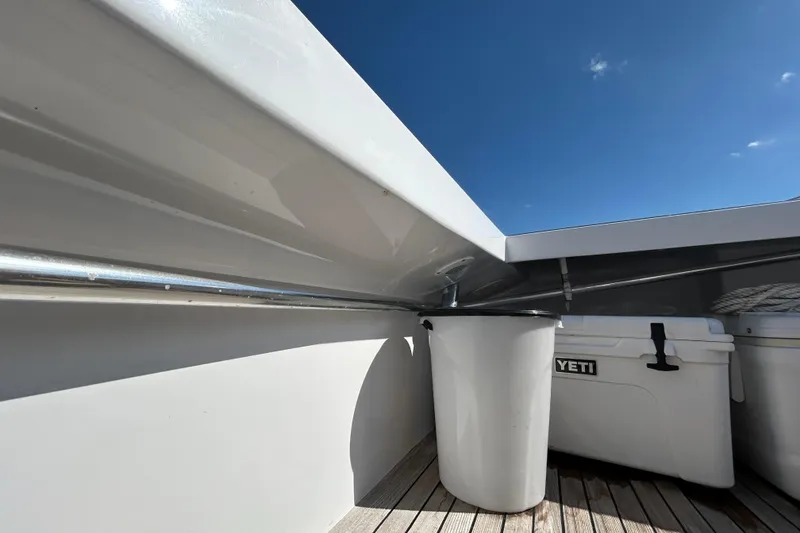 Slide: The Image of 1995 Holland Pettegrow Cruiser deck with Yeti cooler and trash bin under clear blue sky. - 10