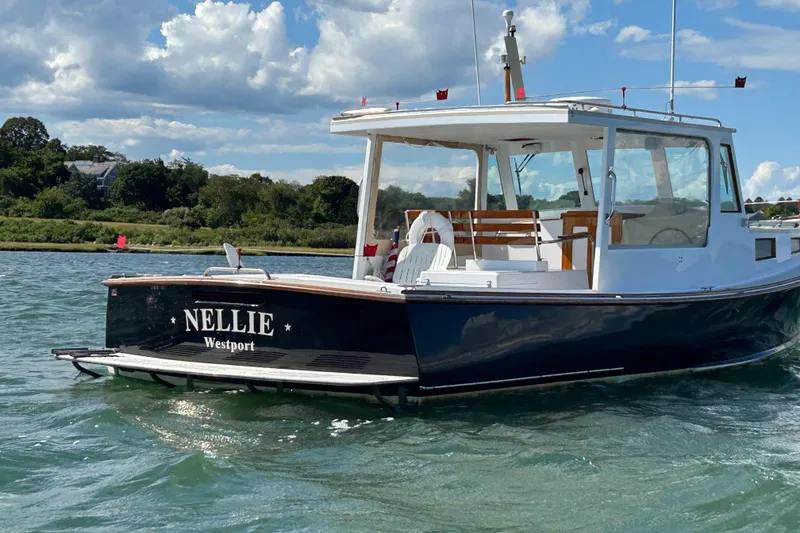 Slide: The Image of 1995 Holland Pettegrow Cruiser "Nellie" on water, scenic background, clear sky. - 2