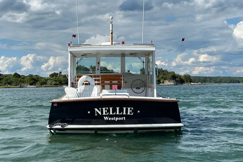 Slide: The Image of 1995 Holland Pettegrow Cruiser "Nellie" on water, scenic backdrop, partly cloudy sky. - 31