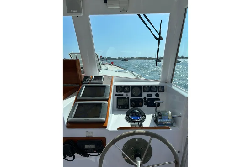 Slide: The Image of 1995 Holland Pettegrow Cruiser helm with navigation instruments, steering wheel, and water view. - 32