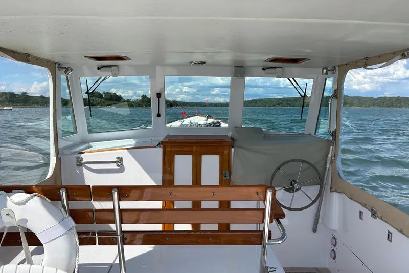 Slide: The Image of 1995 Holland Pettegrow Cruiser interior with wooden accents, steering wheel, and scenic water view. - 5