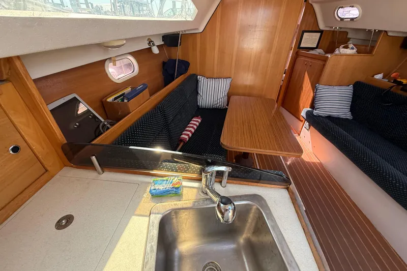 Slide: The Image of Interior of a 2008 Catalina 310 sailboat with cozy seating and wooden table. - 19