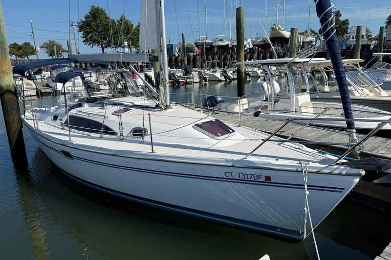 Slide: The Image of 2008 Catalina 310 sailboat docked in a marina, surrounded by other boats. - 2
