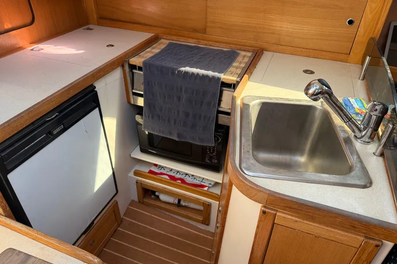 Slide: The Image of Compact kitchen area in a 2008 Catalina 310 sailboat with sink, fridge, and microwave. - 9