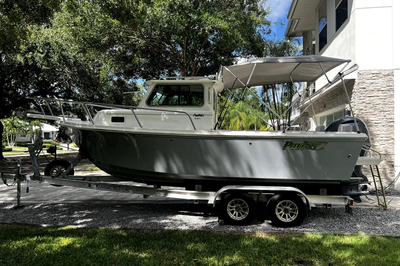 Slide: The Image of 2023 Parker 2120 Sport Cabin boat on trailer, parked outdoors near a house. - 12