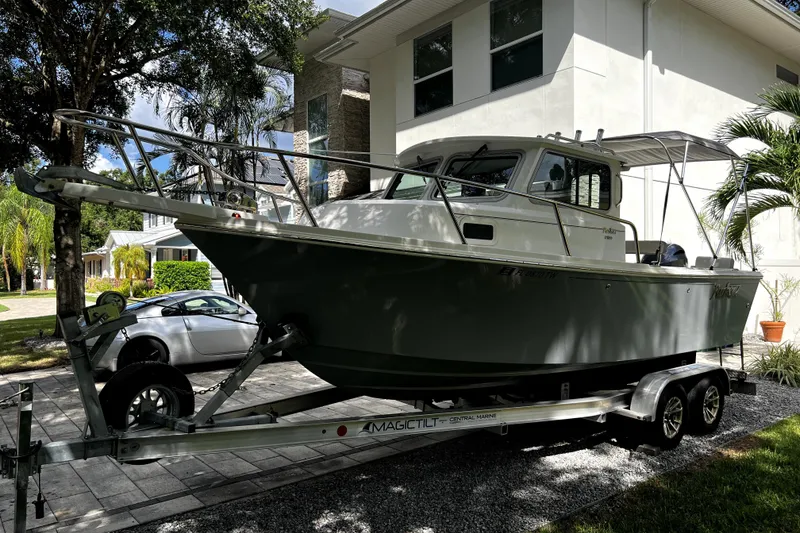 Slide: The Image of 2023 Parker 2120 Sport Cabin boat on trailer, parked near modern house. - 13