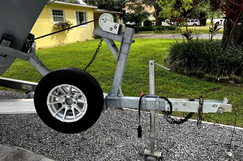 Slide: The Image of Trailer hitch and wheel of a 2023 Parker 2120 Sport Cabin boat on gravel driveway. - 16