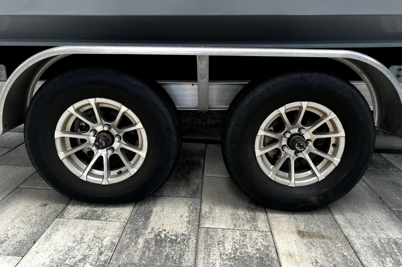 Slide: The Image of Trailer wheels of a 2023 Parker 2120 Sport Cabin boat on a paved surface. - 18