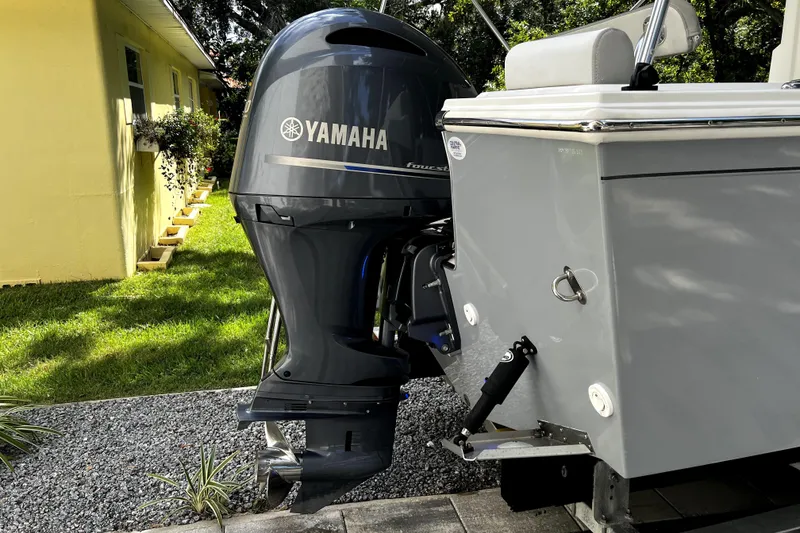 Slide: The Image of 2023 Parker 2120 Sport Cabin with Yamaha outboard motor, parked on gravel near a yellow house. - 3