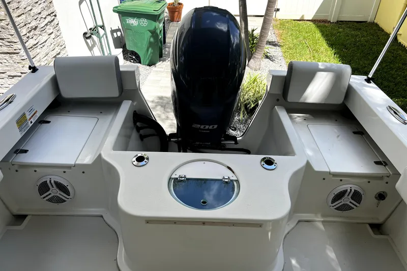 Slide: The Image of 2023 Parker 2120 Sport Cabin boat interior with motor and seating area. - 36