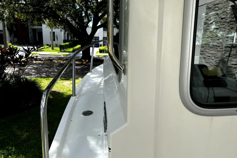 Slide: The Image of 2023 Parker 2120 Sport Cabin boat exterior with railing and window, parked outdoors. - 45