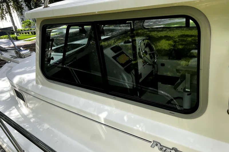 Slide: The Image of 2023 Parker 2120 Sport Cabin boat with reflective windows and visible steering wheel. - 47