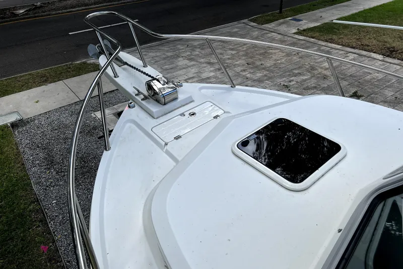 Slide: The Image of 2023 Parker 2120 Sport Cabin boat deck with anchor and hatch, parked on gravel. - 49