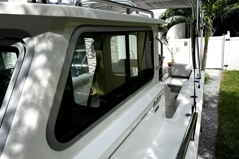 Slide: The Image of 2023 Parker 2120 Sport Cabin boat, side view with windows and seating, outdoors. - 51