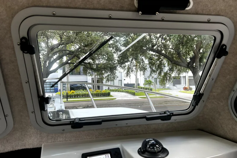Slide: The Image of Interior view from a 2023 Parker 2120 Sport Cabin boat, showing a window and compass. - 73