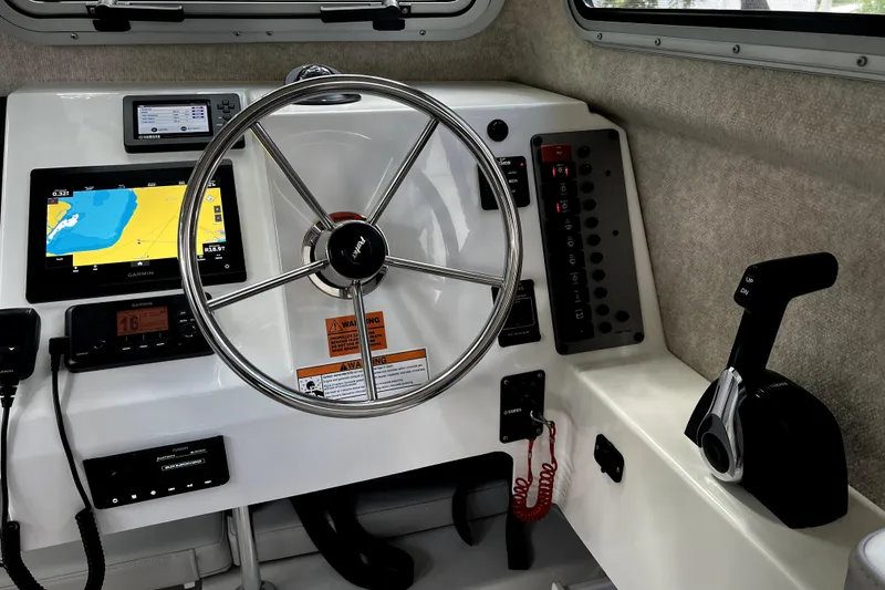 Slide: The Image of 2023 Parker 2120 Sport Cabin helm with steering wheel, navigation screens, and control panel. - 77