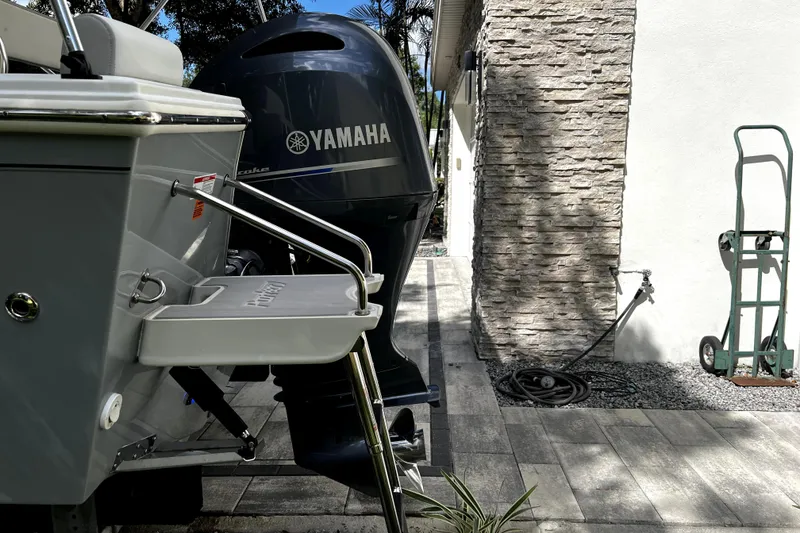 Slide: The Image of 2023 Parker 2120 Sport Cabin boat with Yamaha outboard motor, parked near stone wall. - 9