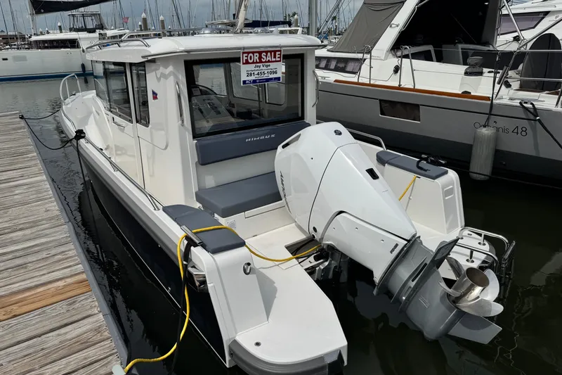 Slide: The Image of 2025 Nimbus Commuter 9 boat docked, for sale sign visible, sleek design, powerful outboard motor. - 2