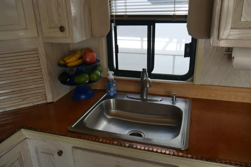 Slide: The Image of 1996 STARDUST Cruiser kitchen with white cabinets, stainless steel appliances, and wooden countertops. - 18