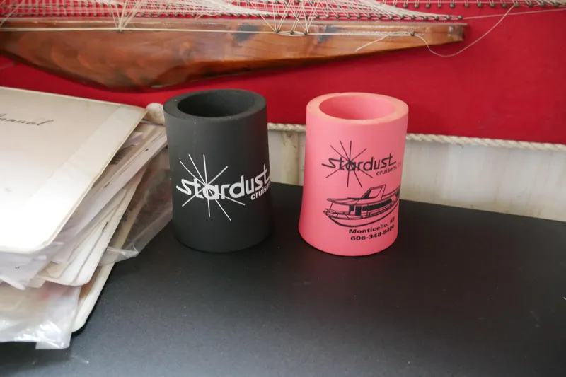 Slide: The Image of Two Stardust Cruiser can holders, black and pink, on a table with documents. - 61