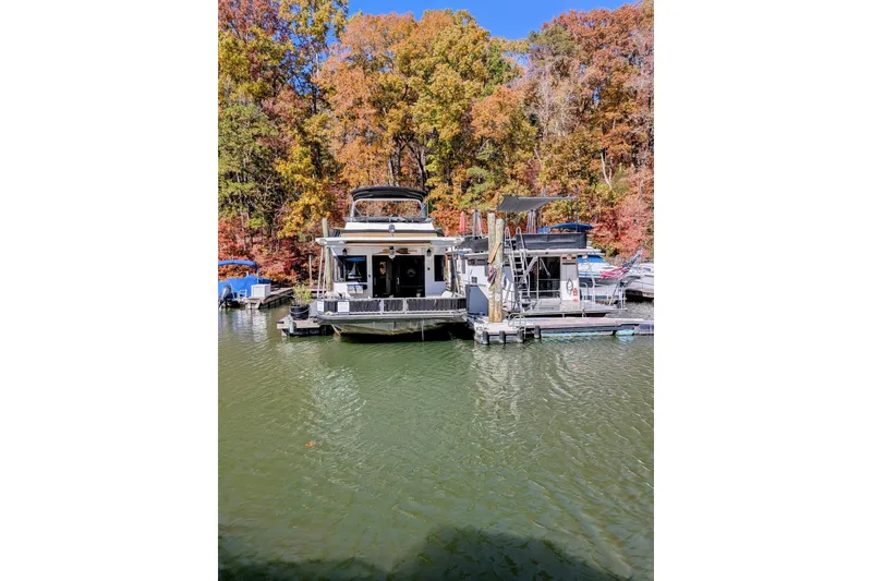 Slide: The Image of 1996 Stardust Cruisers houseboat docked on a lake with vibrant autumn foliage. - 64