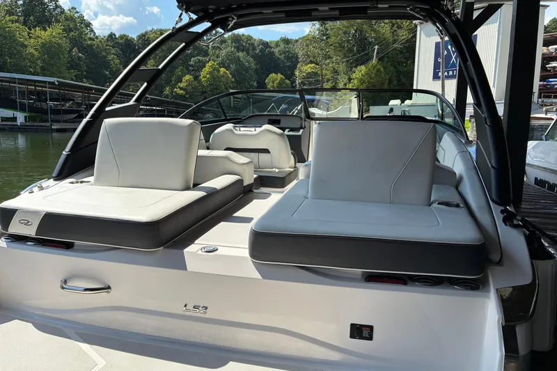 Slide: The Image of 2025 Regal LS2 boat interior with sleek seating, docked by a scenic lake. - 15