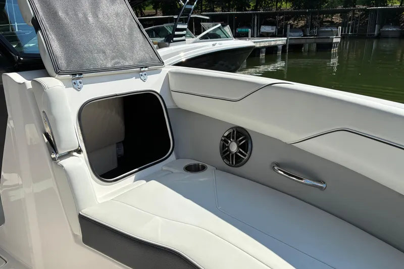 Slide: The Image of 2025 Regal LS2 boat interior with storage compartment and speaker, docked by the water. - 21