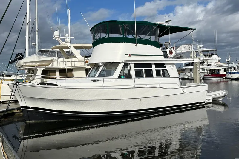 Slide: The Image of 2001 Mainship 390 Trawler docked at marina, featuring green canopy and white hull. - 0