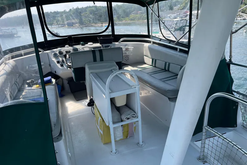 Slide: The Image of 2001 Mainship 390 Trawler interior with seating and helm, docked by scenic waterfront. - 19