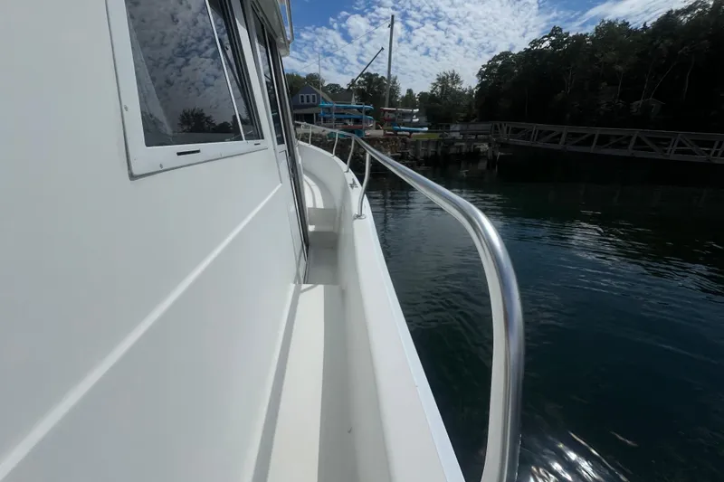 Slide: The Image of 2001 Mainship 390 Trawler docked, side view with railing and water reflection. - 22