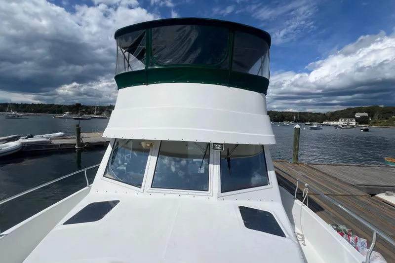 Slide: The Image of 2001 Mainship 390 Trawler docked at a scenic marina under a partly cloudy sky. - 25