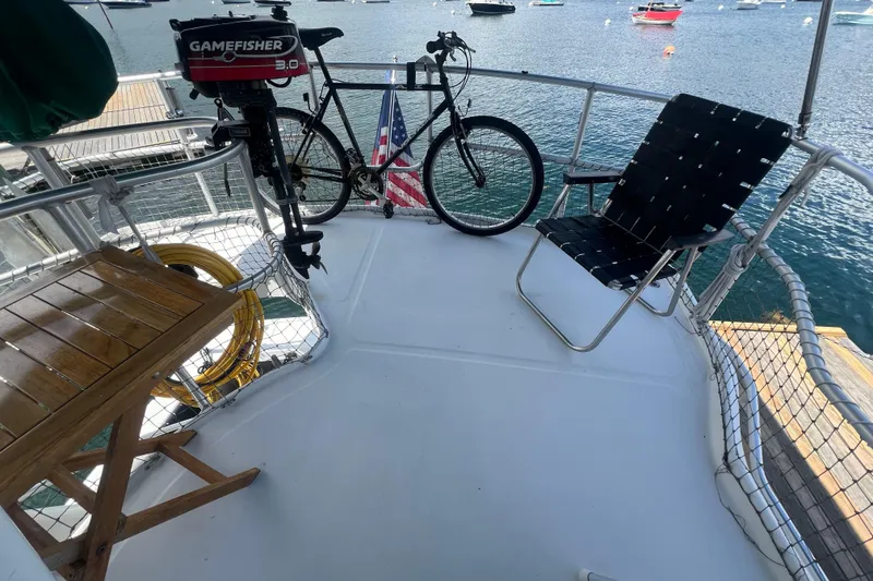 Slide: The Image of Deck of 2001 Mainship 390 Trawler with chair, bicycle, and motor overlooking water. - 26