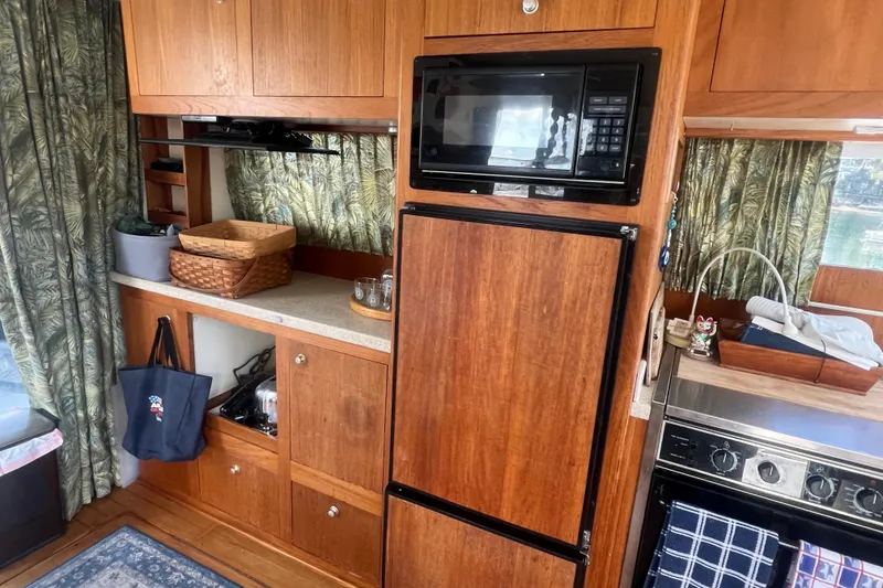Slide: The Image of 2001 Mainship 390 Trawler kitchen with wooden cabinets, microwave, and refrigerator. - 4