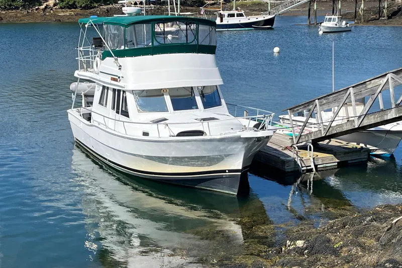 Slide: The Image of 2001 Mainship 390 Trawler docked in a serene marina setting. - 40