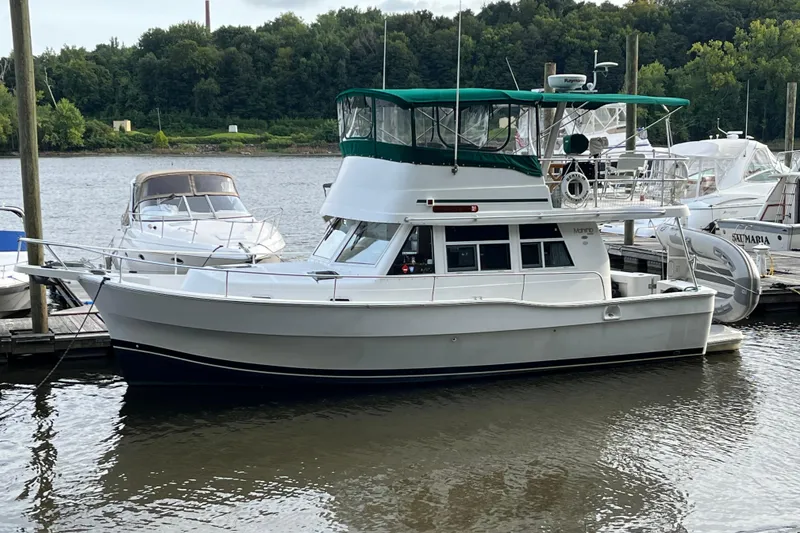 Slide: The Image of 2001 Mainship 390 Trawler docked by the river, featuring a green canopy. - 41