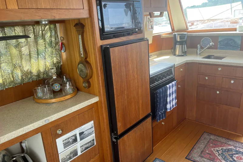 Slide: The Image of 2001 Mainship 390 Trawler kitchen with wood cabinetry, appliances, and decorative accents. - 5
