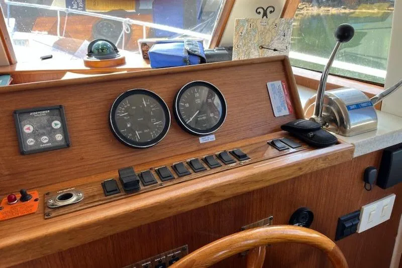 Slide: The Image of 2001 Mainship 390 Trawler helm with gauges, controls, and wooden steering wheel. - 8