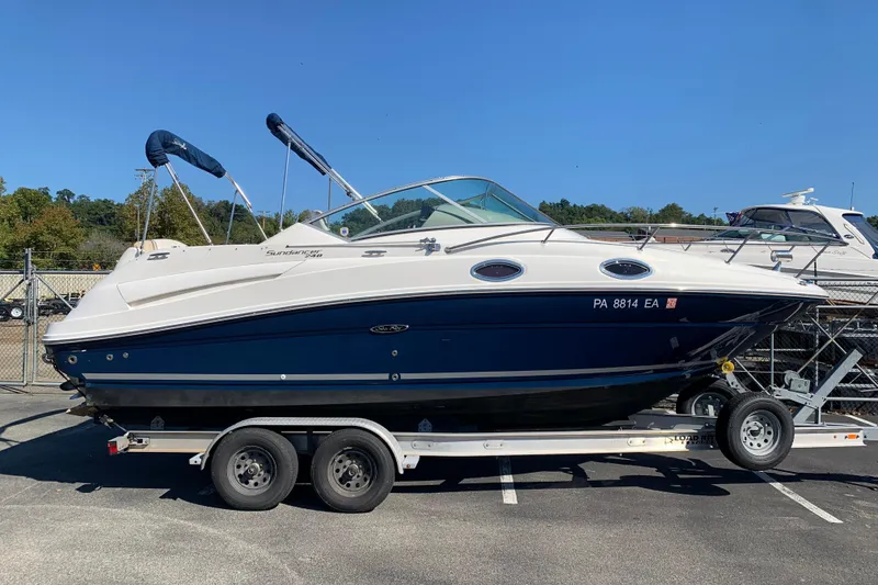 The Image of 2013 Sea Ray 240 Sundancer boat on trailer, parked outdoors under clear blue sky. - 1