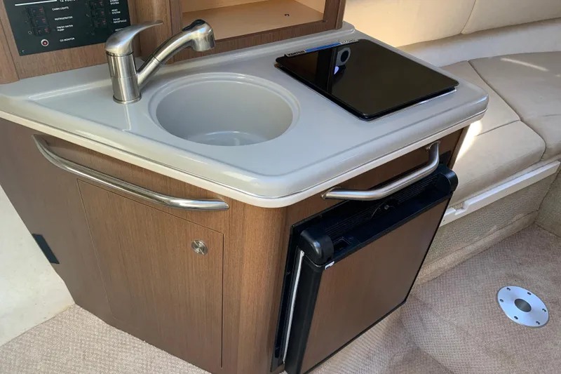 Slide: The Image of 2013 Sea Ray 240 Sundancer cabin with sink, countertop, and mini fridge. - 8
