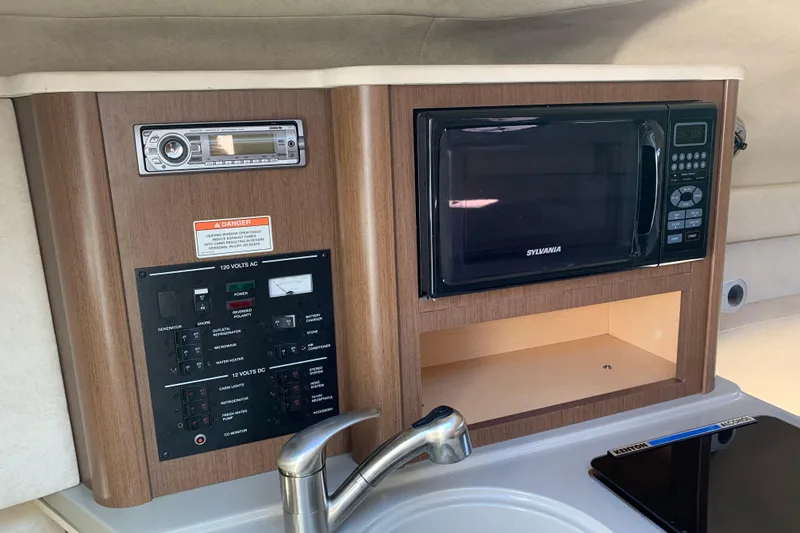 Slide: The Image of 2013 Sea Ray 240 Sundancer interior with microwave, control panel, and sink. - 9