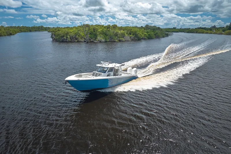 Slide: The Image of 2022 Solace 41 CS boat cruising on a scenic river under a cloudy sky. - 2