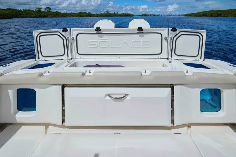 Slide: The Image of 2022 Solace 41 CS boat with open storage compartments on a serene water backdrop. - 9