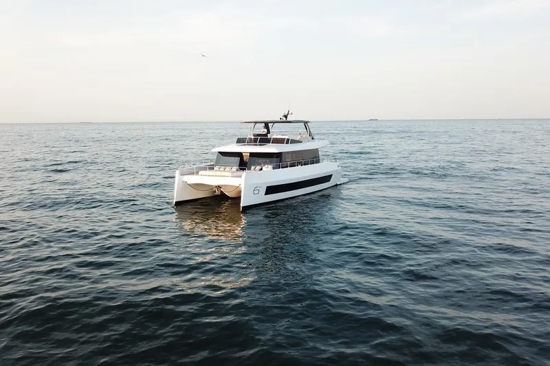 Slide: The Image of 2026 Moon Yachts 6ty catamaran cruising on open sea under clear sky. - 38