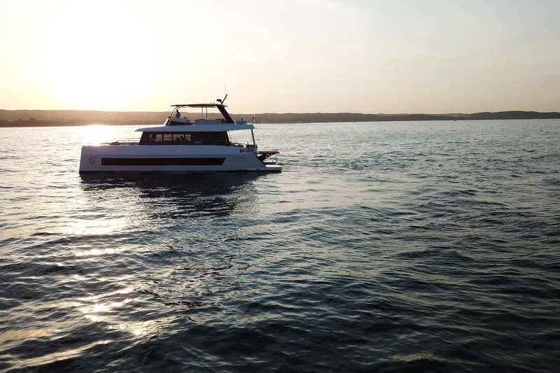 Slide: The Image of Moon Yachts 6ty 2026 sailing at sunset on calm waters. - 52