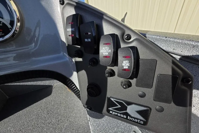 Slide: The Image of Control panel of 2025 Xpress H18C Crappie boat with switches and logo. - 6